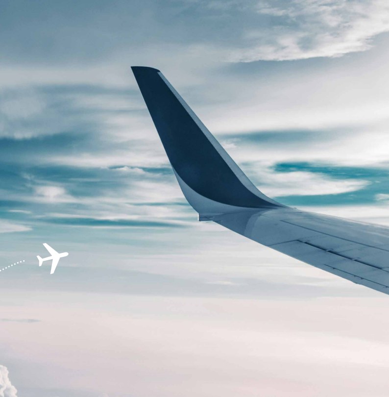An aircraft wing above the clouds, at the beginning of a journey